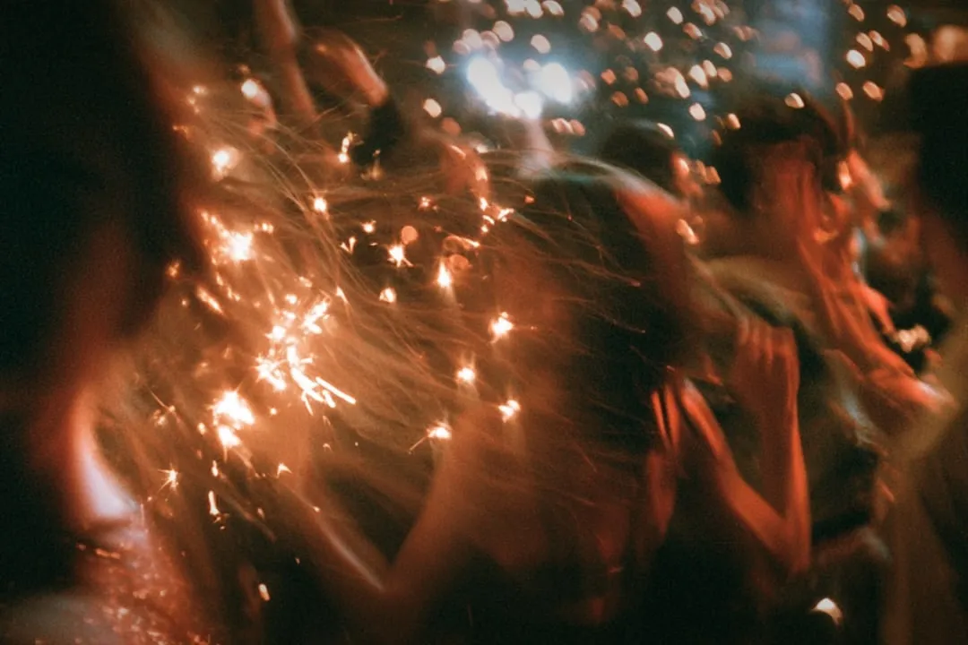 Sparklers scattering light over a crowd standing close together.