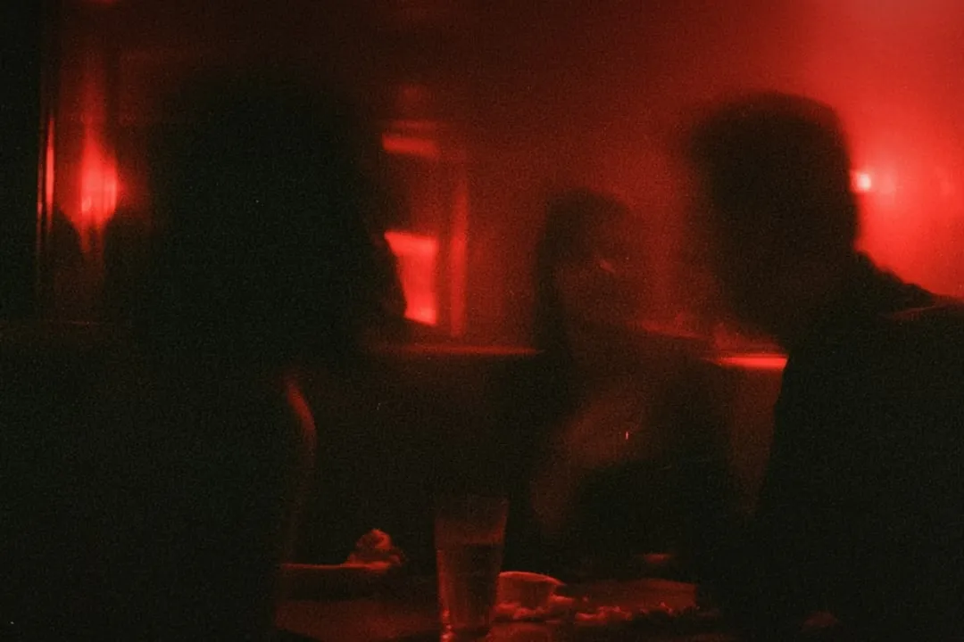 Two people facing each other in a room lit hard red.