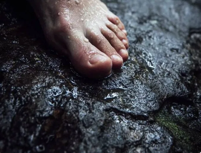 Bare feet on wet black limestone